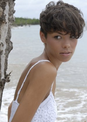 Коротко стриженная девушка Корайл принимает великолепные сольные позы в океанских водах